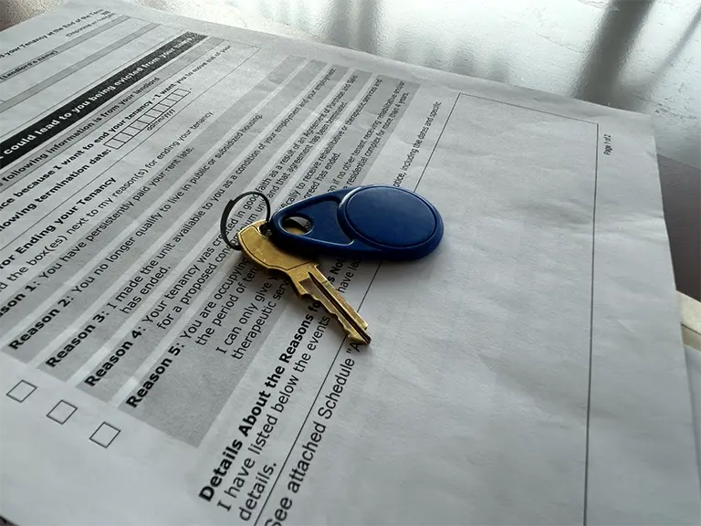 a key and a key fob sitting on landlord and tenant papers