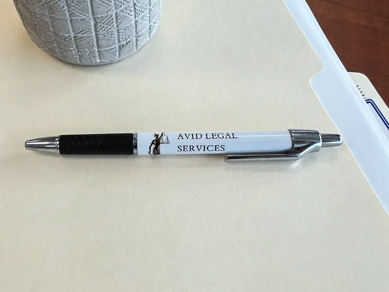 a pen that says AVID Legal Services on a file folder representing notary public