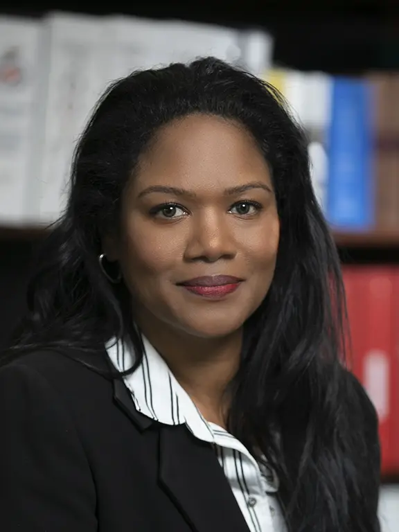 a woman with long hair smiling in-front of a bookshelf