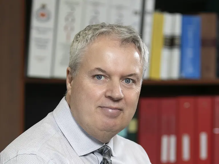 a man in a tie in-front of a bookshelf